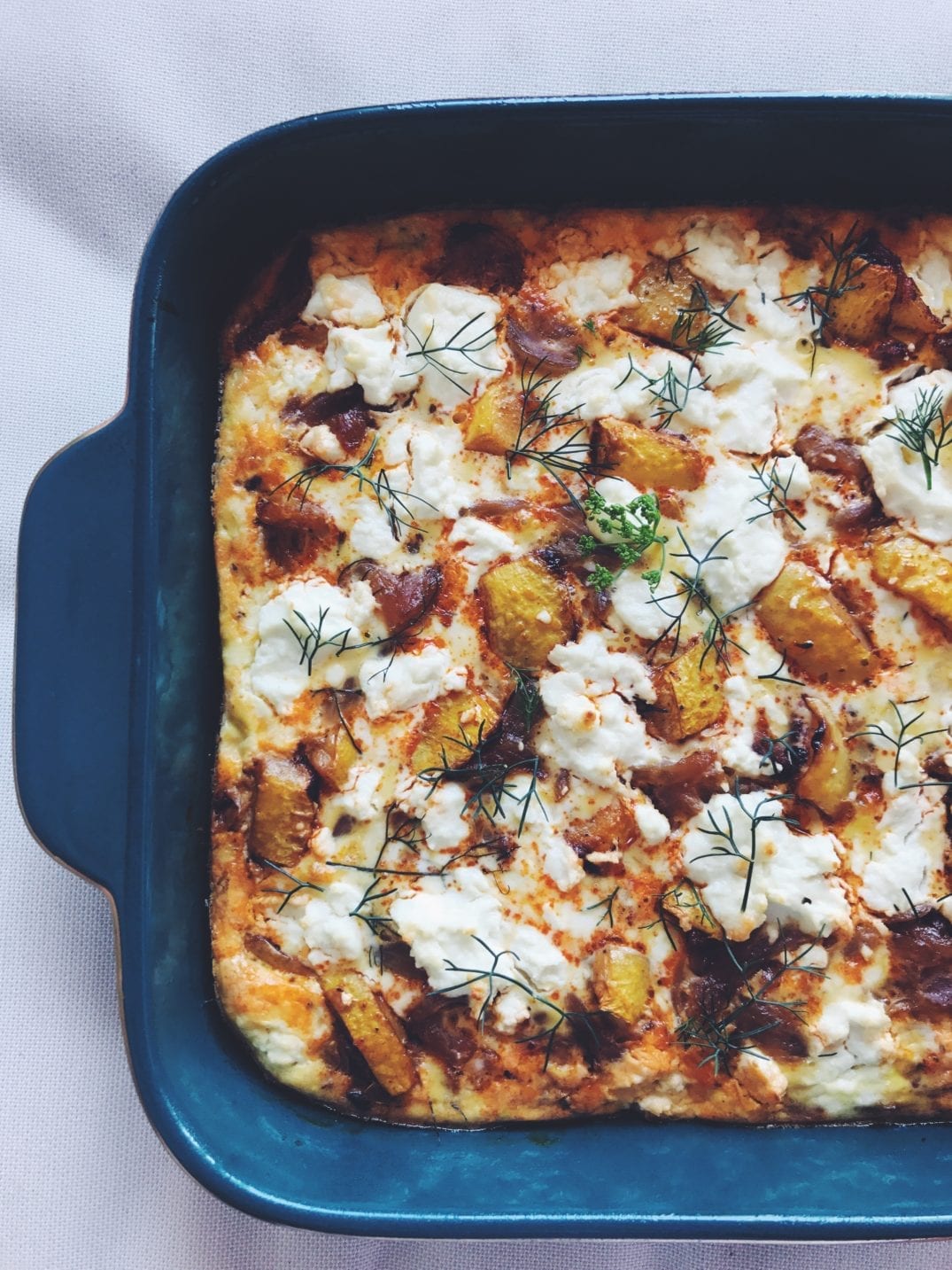Summer Squash Frittata with Goat Cheese, Dill and Caramelized Onions  in a green baking dish