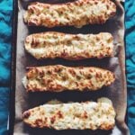 4 pieces of gorgonzola cheesy bread on a baking sheet wiith a blue background
