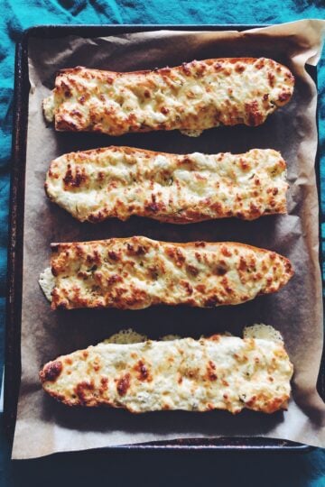4 pieces of gorgonzola cheesy bread on a baking sheet wiith a blue background