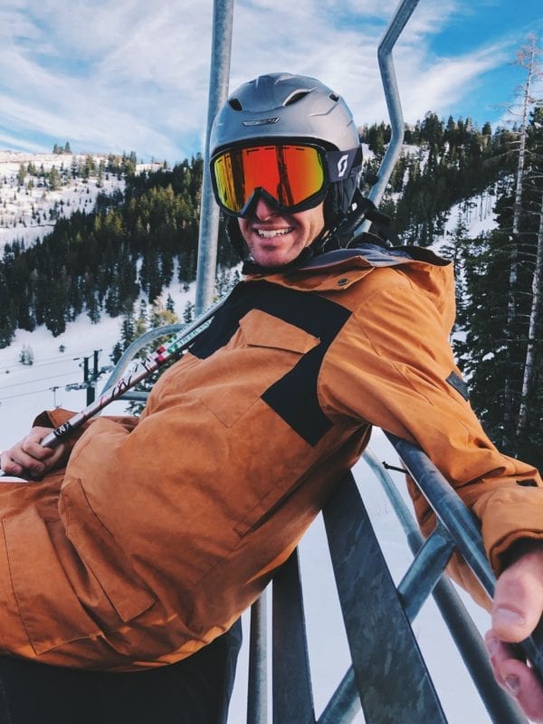 Jeremy Johnston in an orange Dakine Snow Jacket on the ski lift in Deer Valley Utah