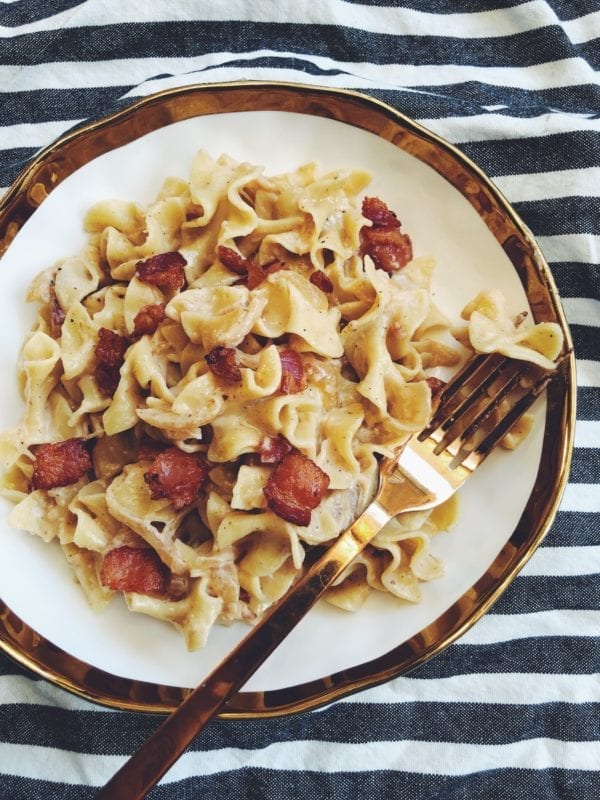 bacon topped mac n cheese in a gold and white bowl with a golden fork and