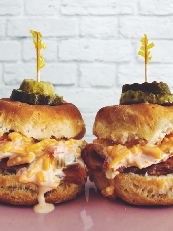 two pimento cheese biscuit sliders on a pink and blue plate with a white background