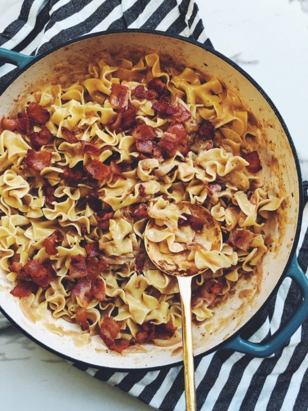 bacon topped mac n cheese in a blue pot with a golden spoon in the right corner