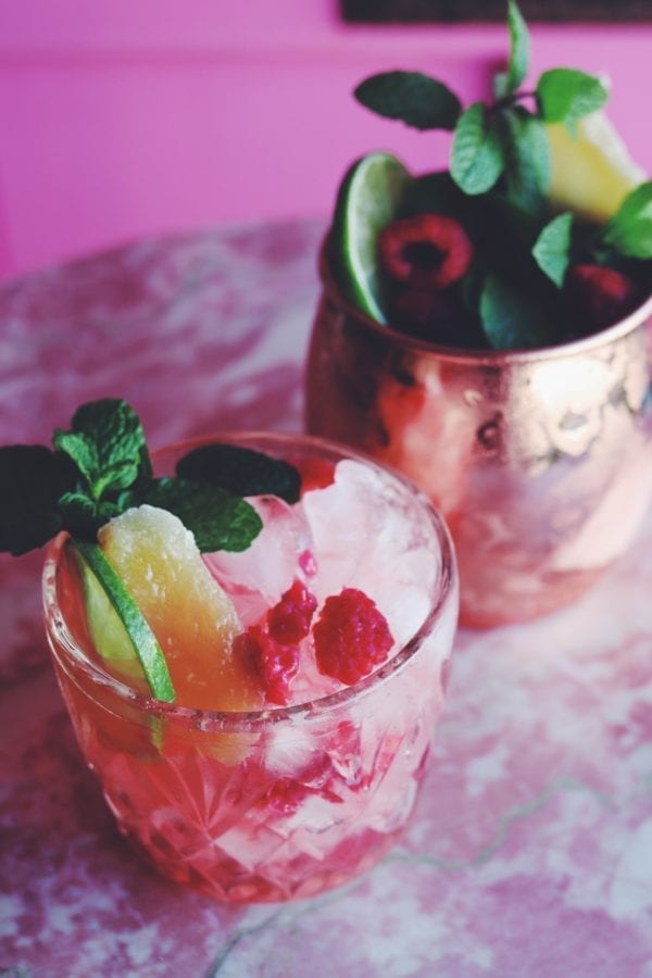 Two pink drinks sitting on a pink marble counter with a pink background