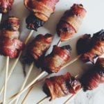 bacon wrapped dates stuffed with blue cheese with a skewer through them on a white countertop
