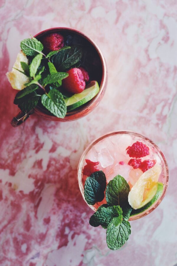 an overhead view of two pink drinks sitting on a pink marble counter 