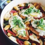 goat cheese topped chicken over a bed of kale, sun dried tomatoes, artichokes and skillet gnocchi in a blue pot