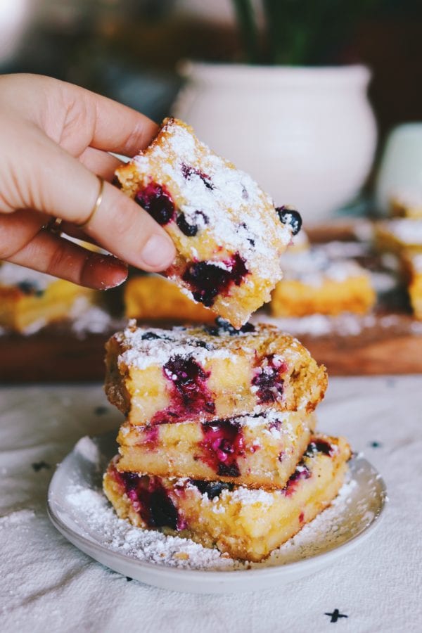 stacked blueberry lemon bars with a hand reaching in