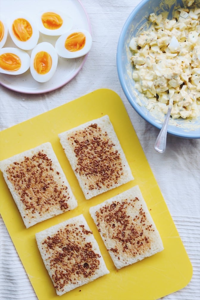 four slices of bread with mustard smeared on them