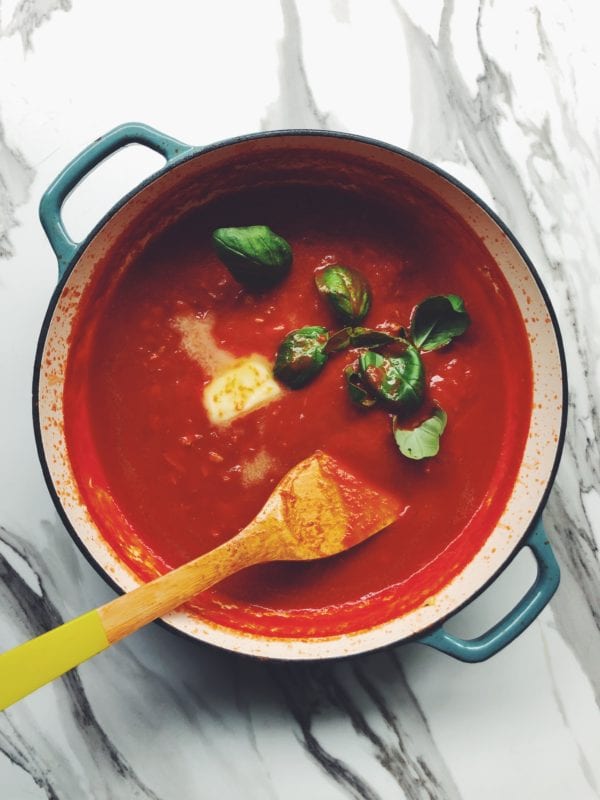 a pot of pomodoro sauce with butter and basil on top