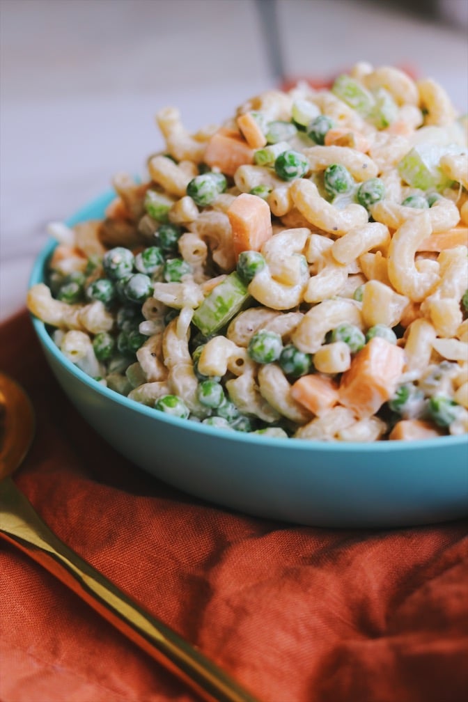 macaroni salad with peas and cheddar in a blue bowl