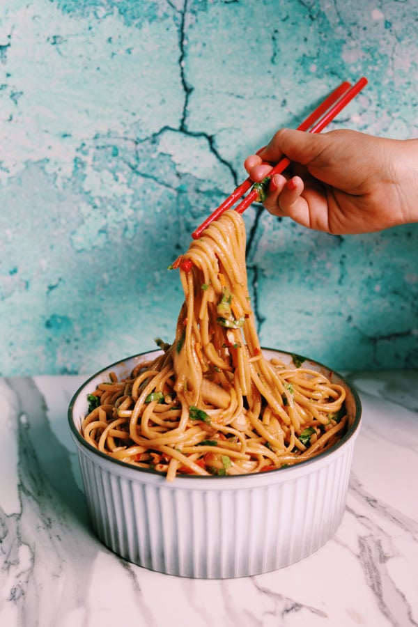 Thai Noodle Salad with Sesame Peanut Sauce in a white bowl with two red chopsticks