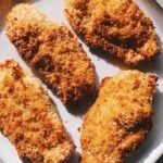 oven baked crispy chicken cutlets on a white plate.