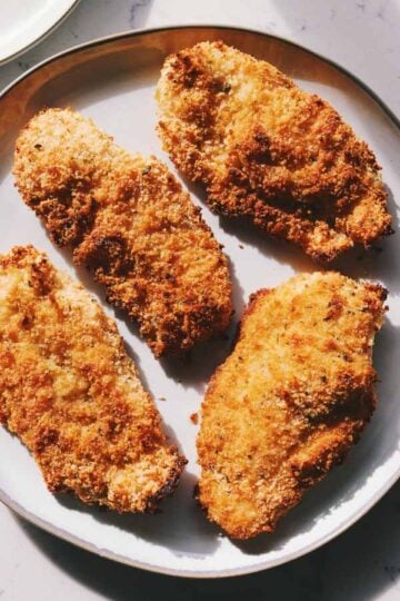 oven baked crispy chicken cutlets on a white plate.