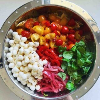 deconstructed caprese pasta salad in a silver bowl on a white countertop.