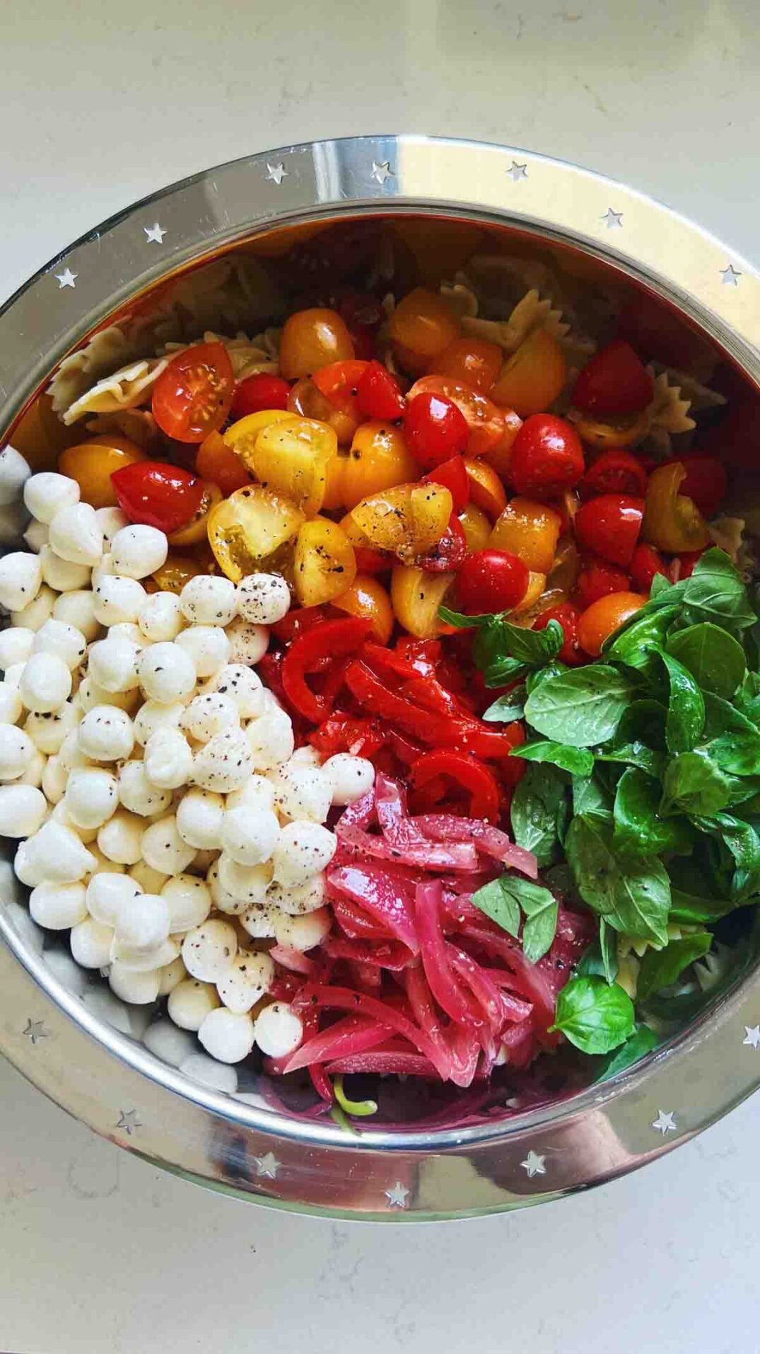 colorful pasta salad ingredients in a silver bowl.