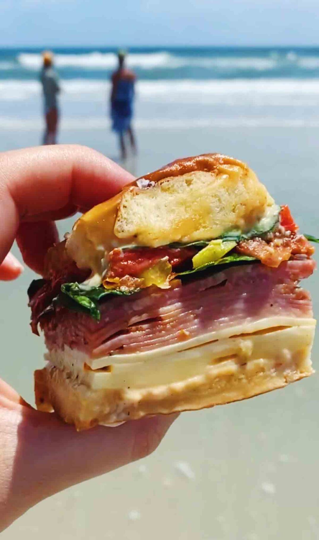 a close up of a a colorful italian slider sandwich at the beach.