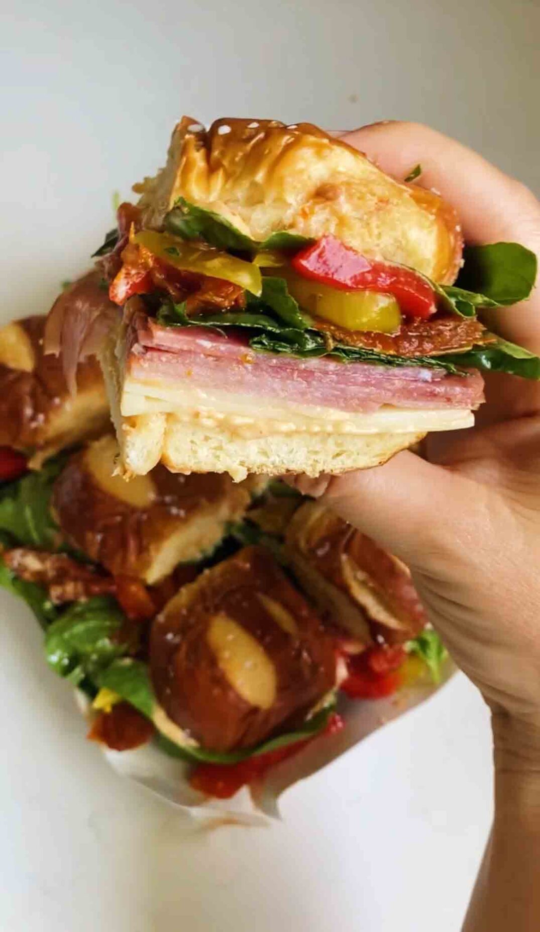 a hand holding a colorful antipasto slider