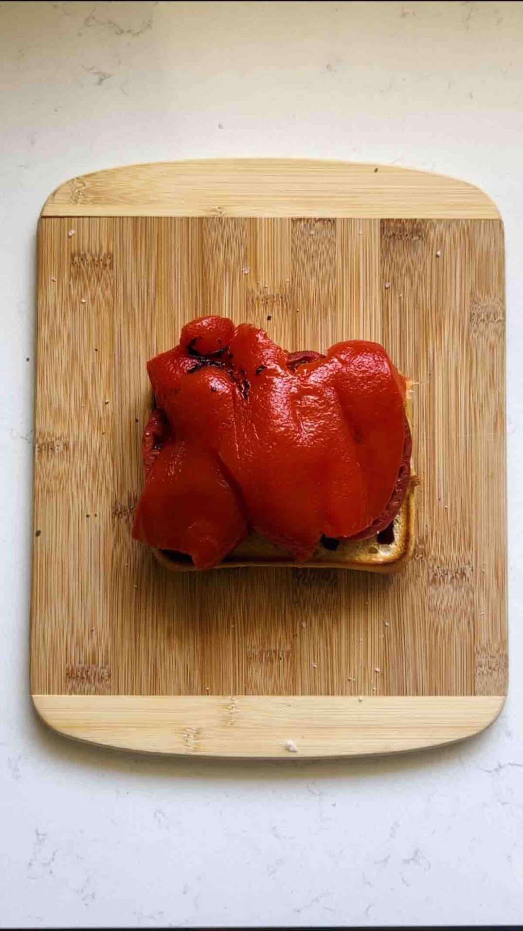 a marinated roasted red pepper on a cutting board.