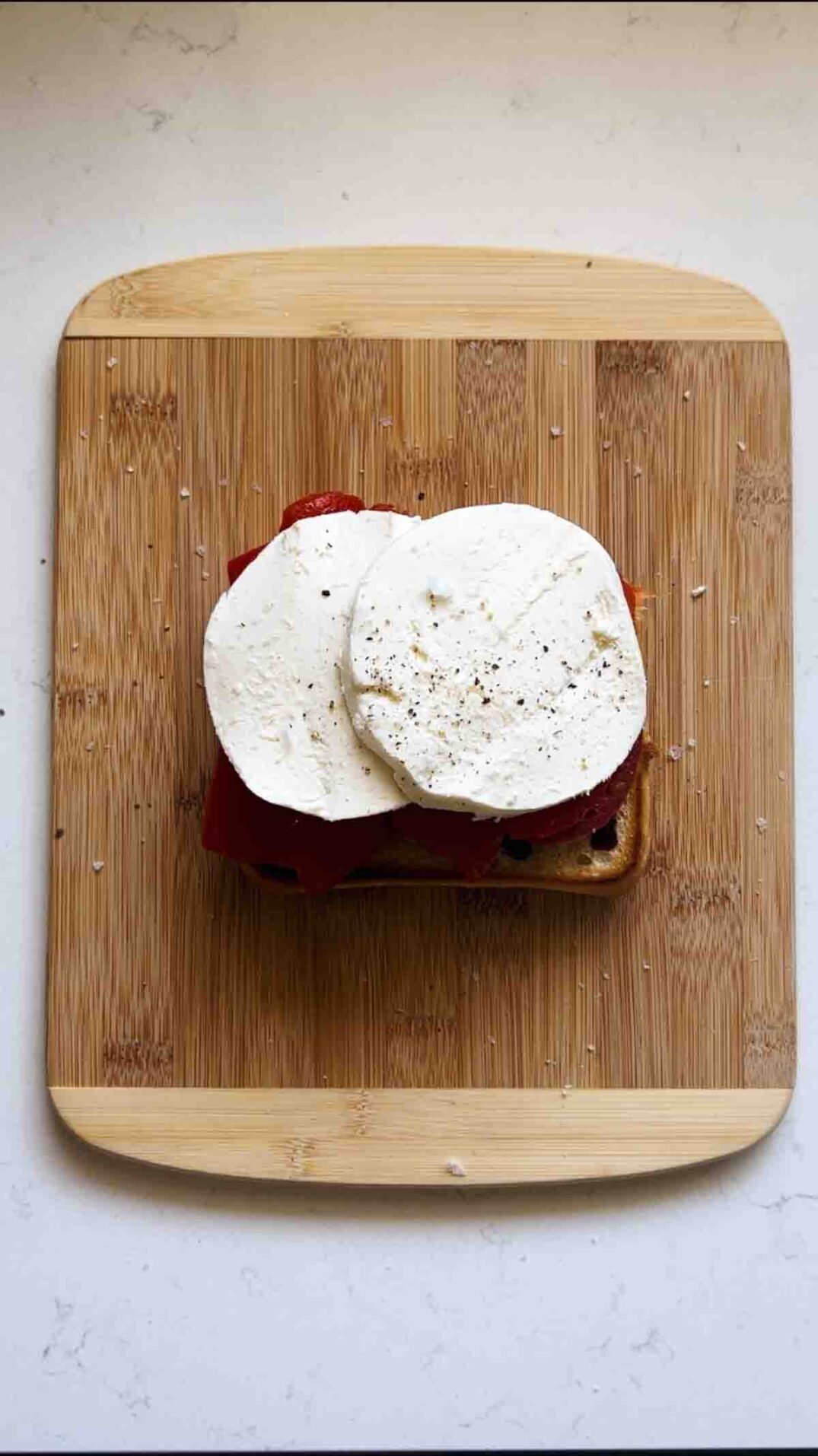 mozzarella with salt and pepper on ciabatta bread on a cutting board.