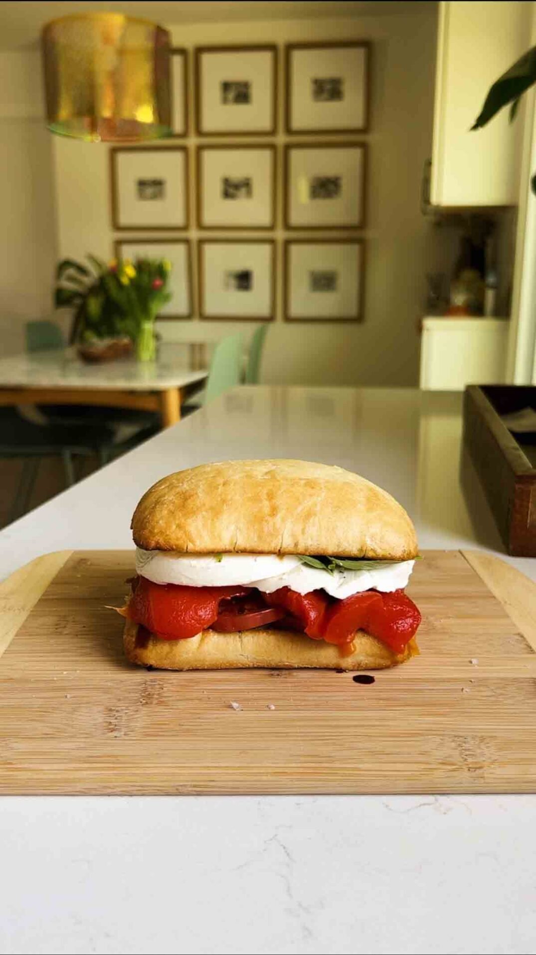 a caprese sandwich sitting on a cutting board.