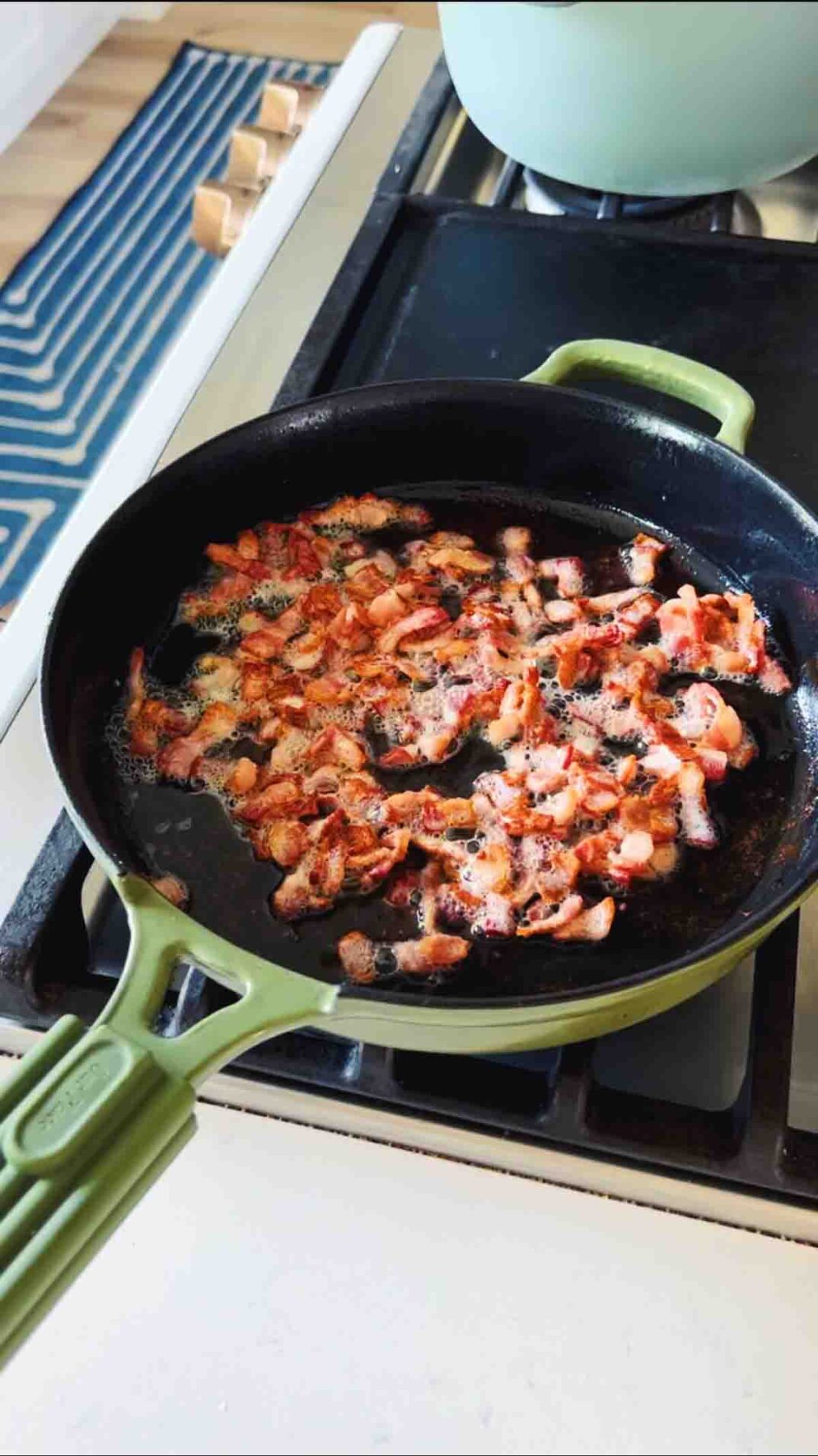 bacon frying in green cast iron skillet.