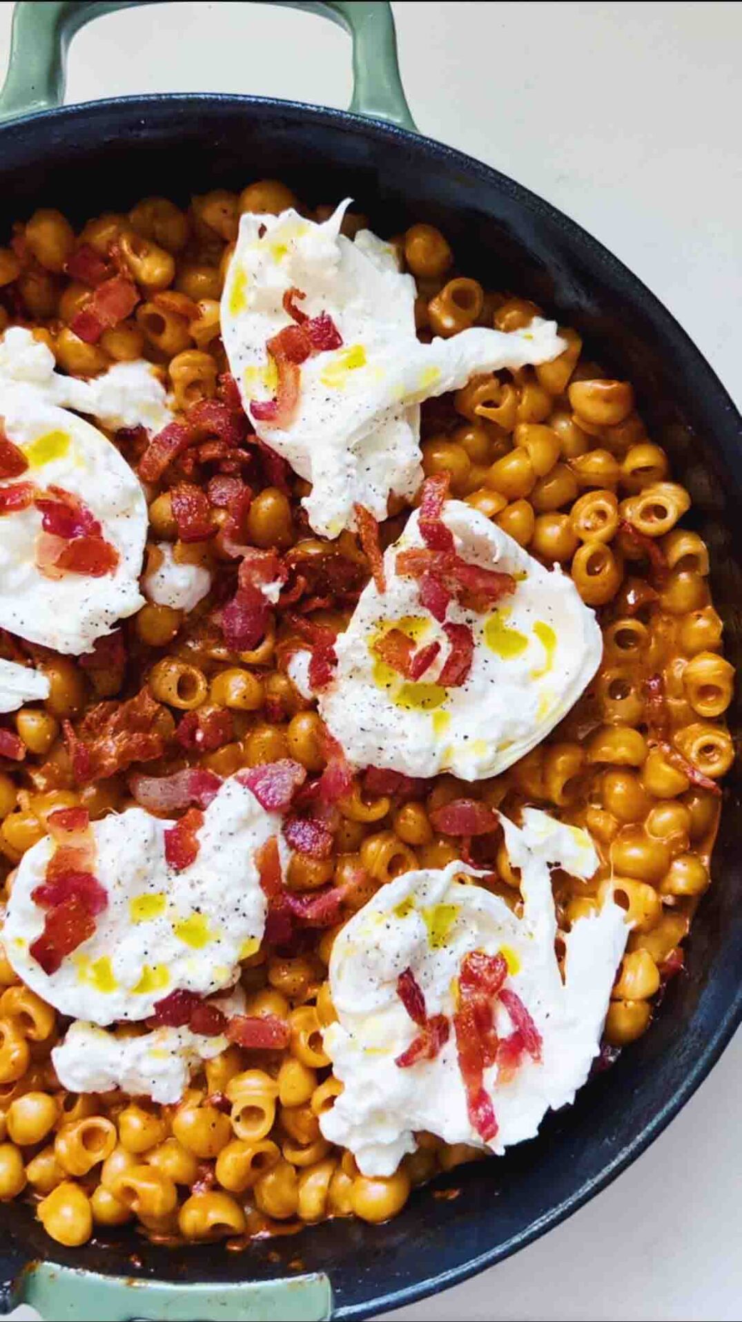 spicy vodka pasta, burrata, and bacon in a skillet on a white surface.