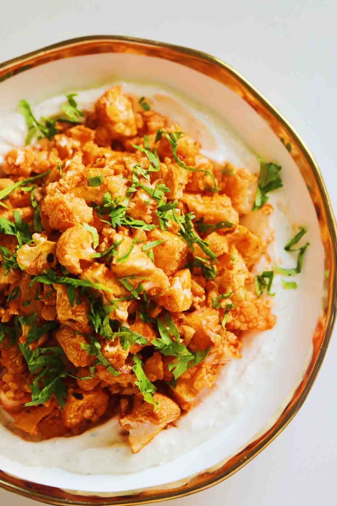 cilantro sprinkled on top of buffalo cauliflower in a bowl