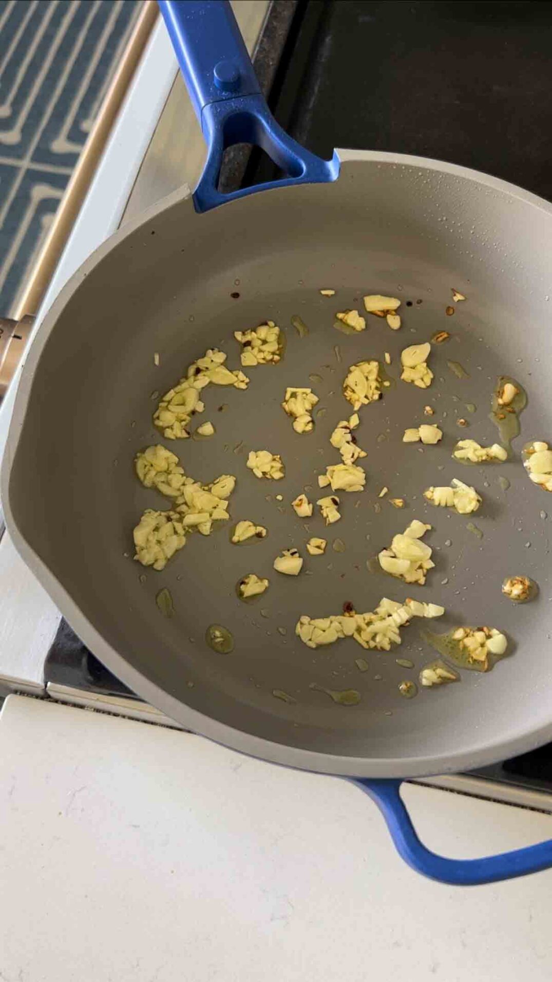 garlic frying in olive oil in a blue pan