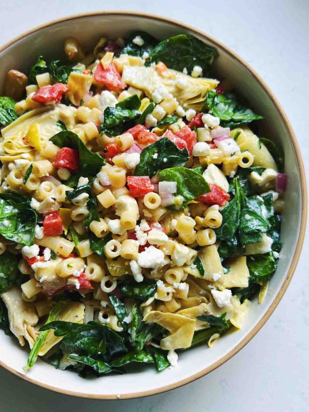 ditalini pasta salad with chopped veggies in a white bowl on a white countertop.