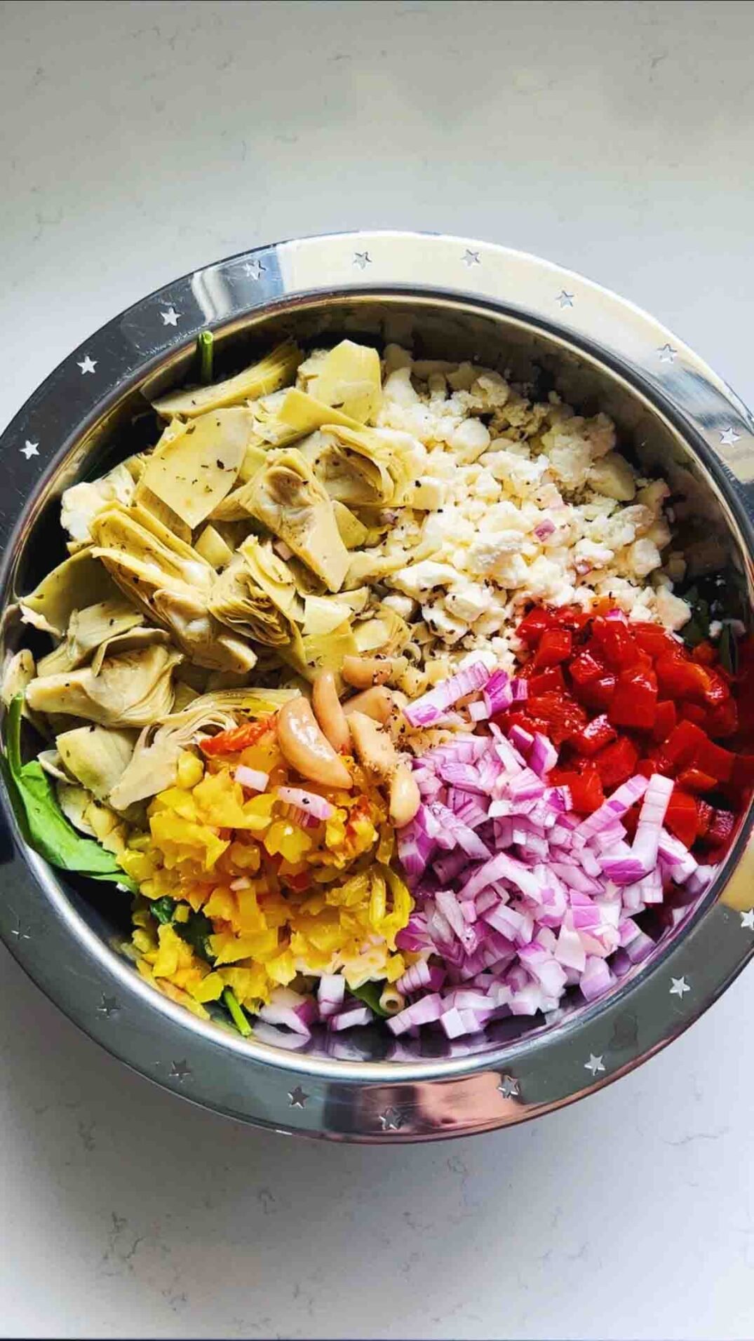 colorful chopped ingredients in a silver bowl on a white countertop.