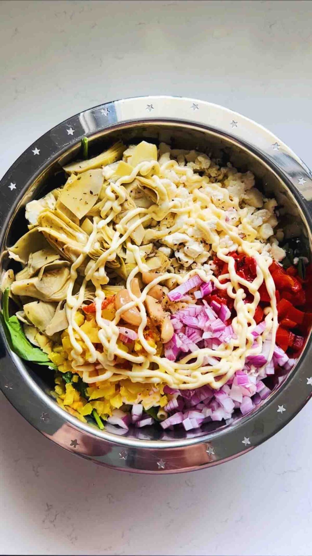 chopped colorful ingredients in a silver bowl on a white countertop.