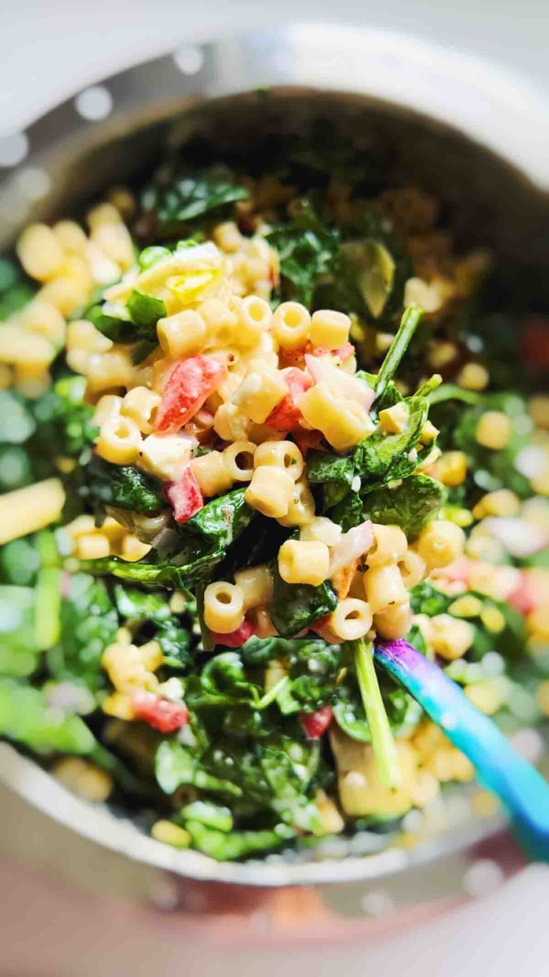 a spoon holding ditalini pasta salad over a blurred out bowl.