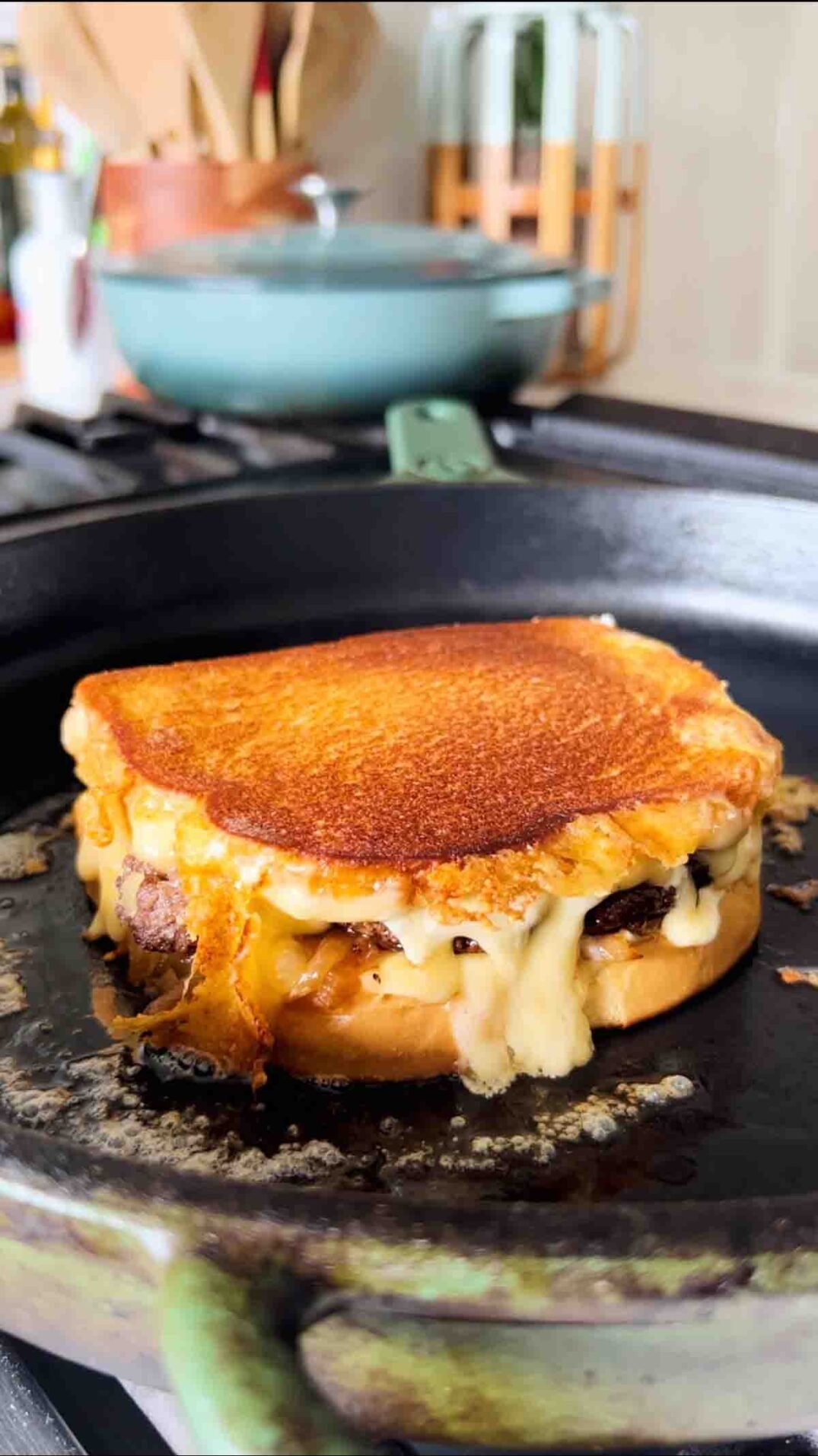 cheese oozing from a grilled cheese in a cast iron skillet.