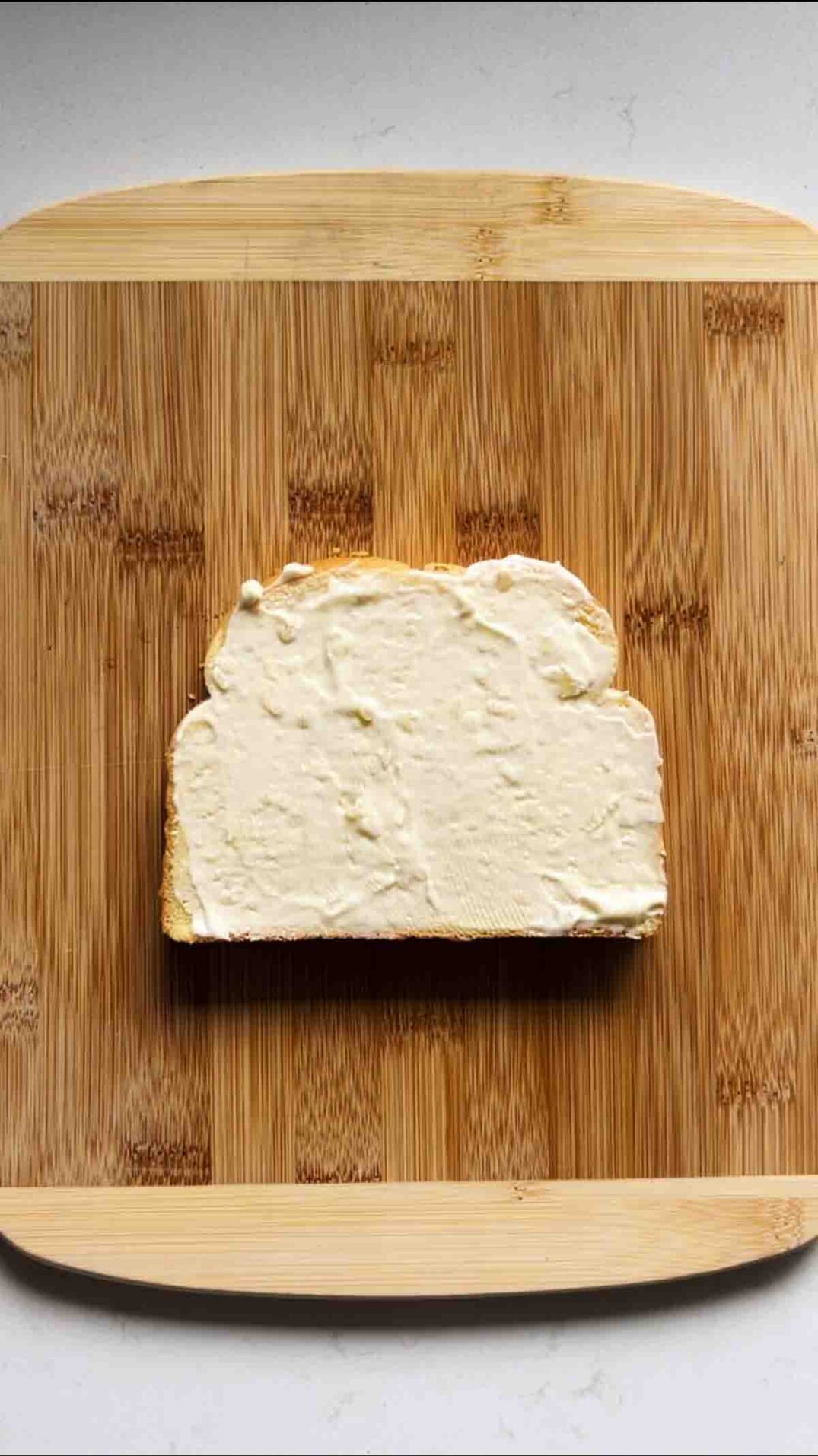 garlic truffle mayo on a slice of bread on a cutting board.