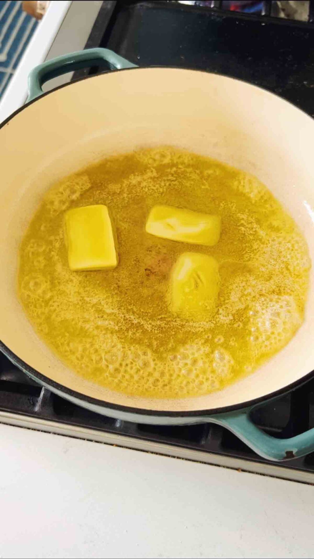 melted butter in a blue braising dish.