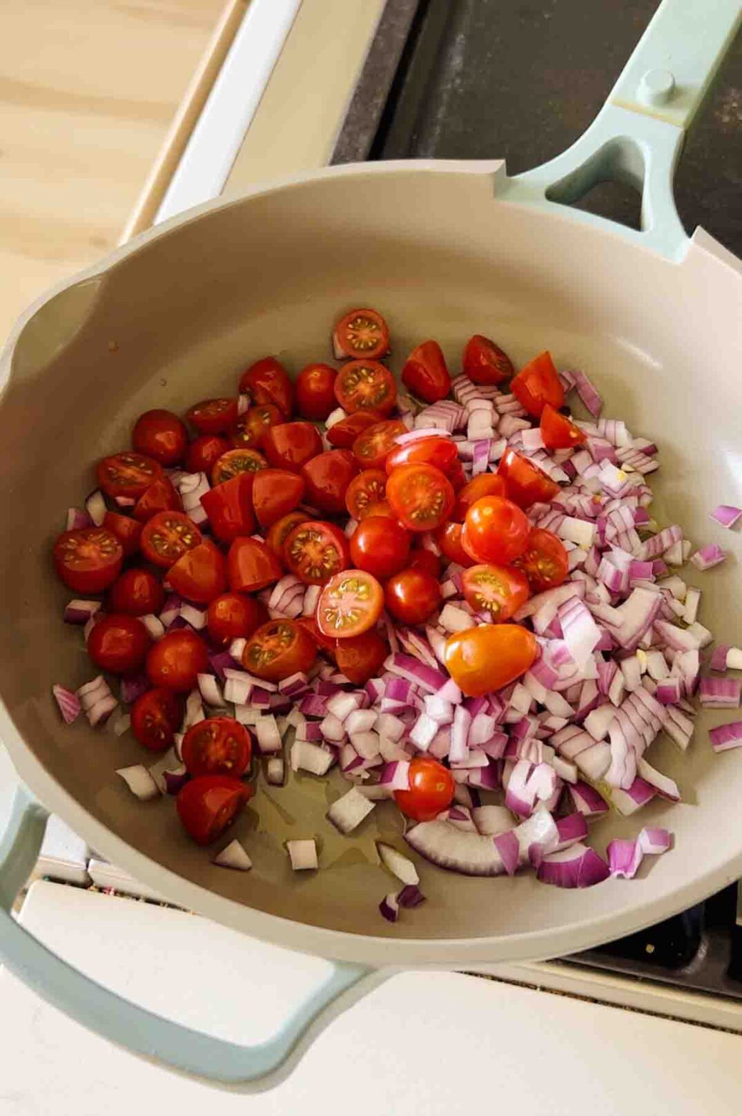 tomatoes and onions cooking in a blue pan.