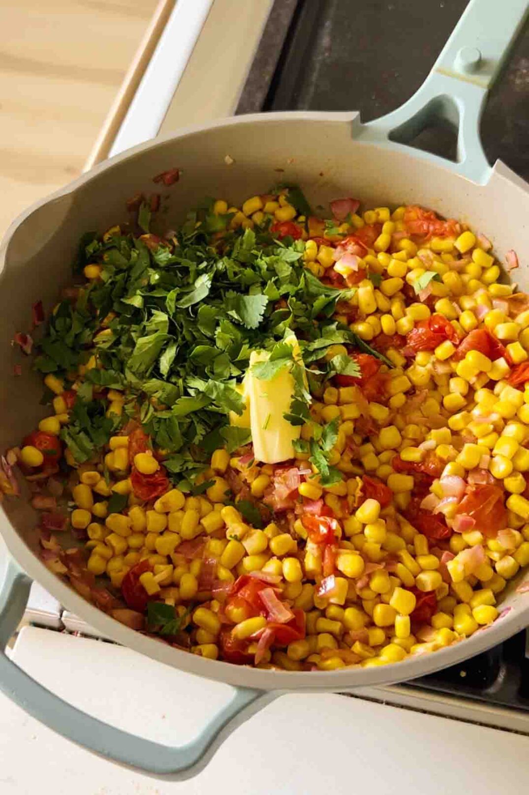 fresh cilantro and butter on top of a sauce pan of 4 rivers smokehouse corn.