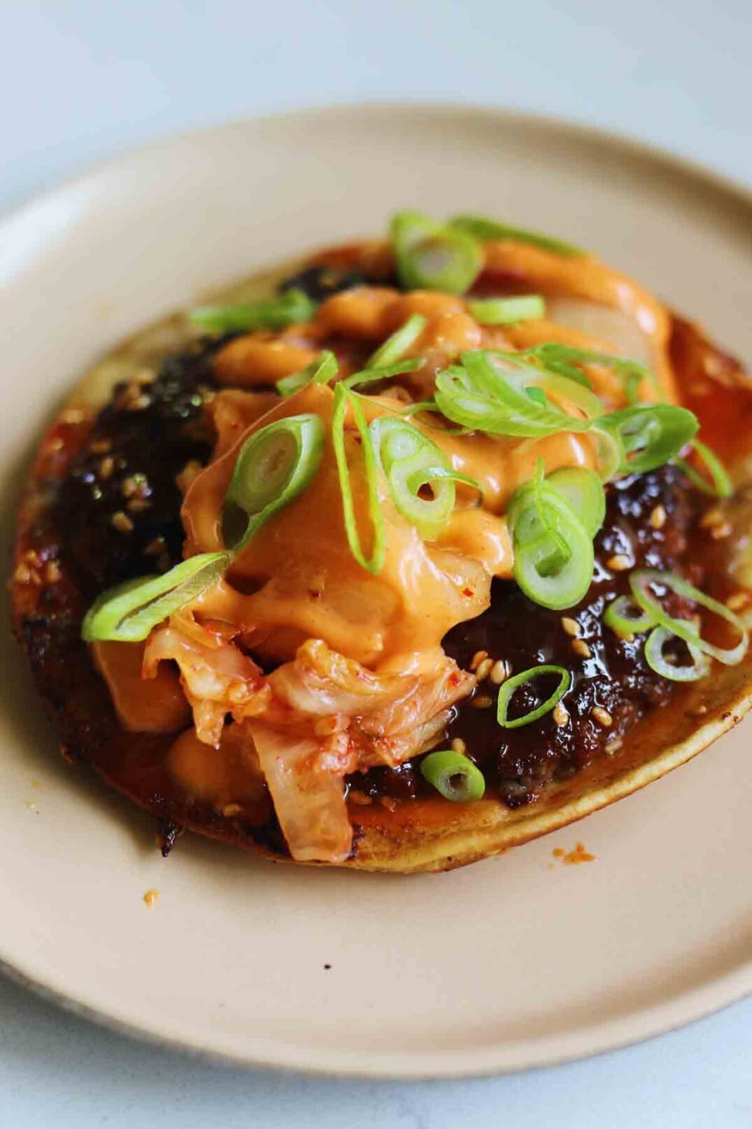 a fully loaded korean smash burger taco topped with kimchi and gochujang mayo