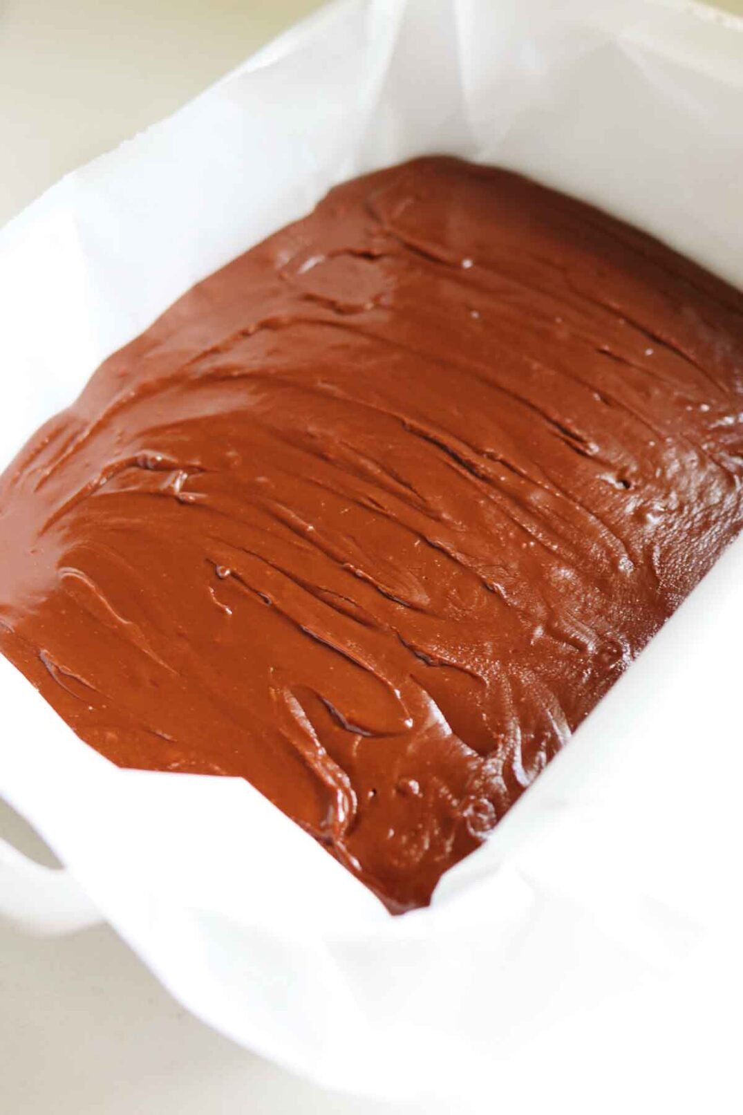 nutella fudge in a white staub baking sheet with parchment paper.