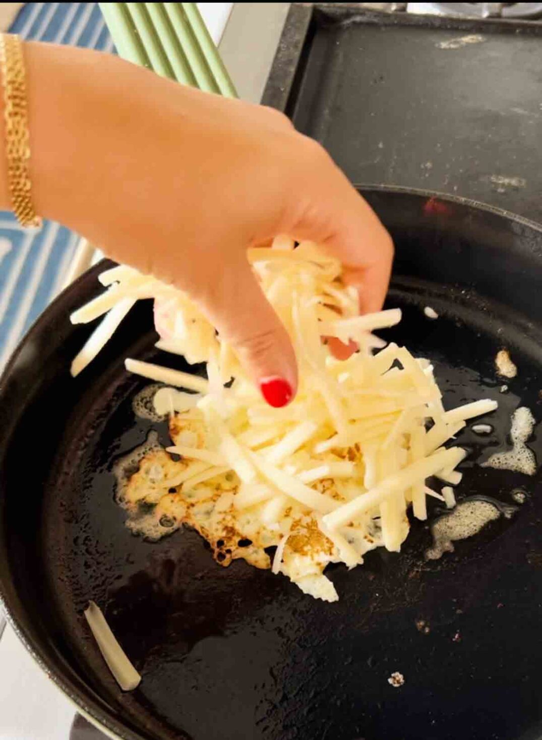 shredded cheese getting put on top of a fried egg.