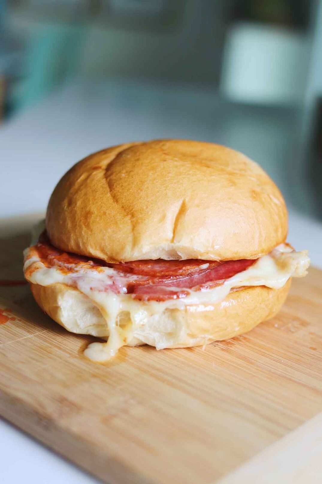 a pork roll egg and cheese sitting on a wooden cutting board with a white blurred out background.