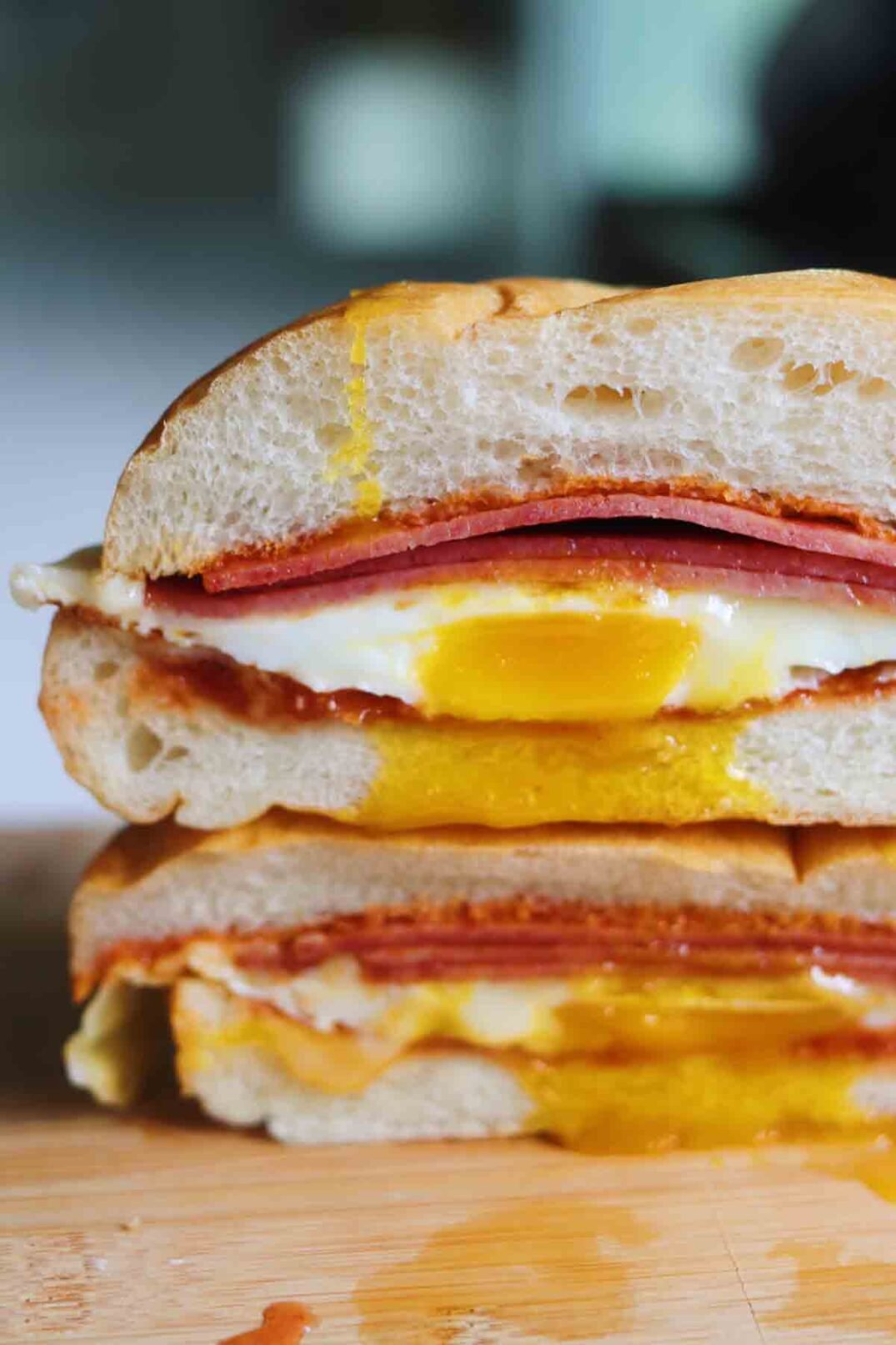 a close up of a pork roll egg and cheese sandwich that's cut in half with egg yolk dripping out.
