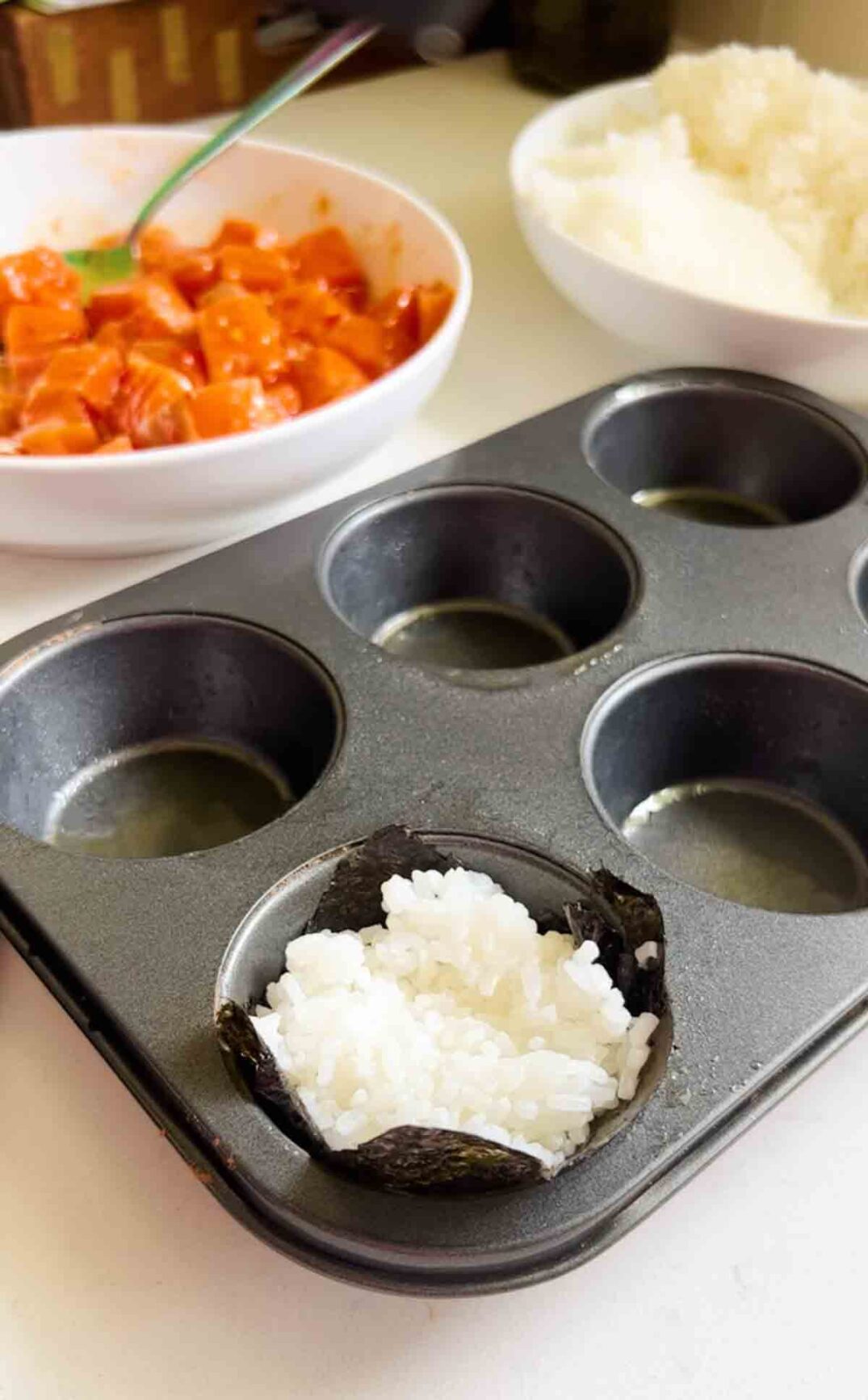 a muffin tin stuffed with nori and sushi rice.