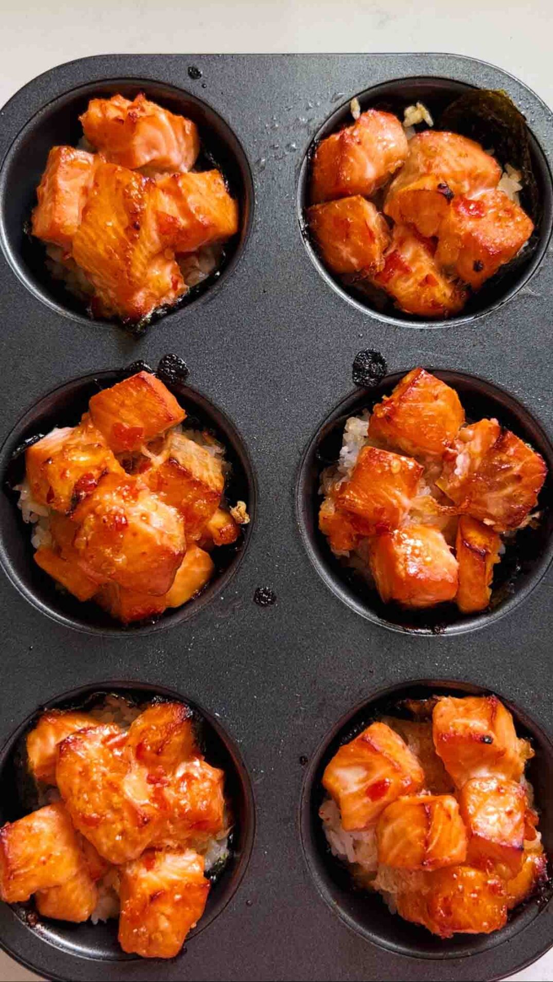 cooked salmon sushi cups in a muffin tin.