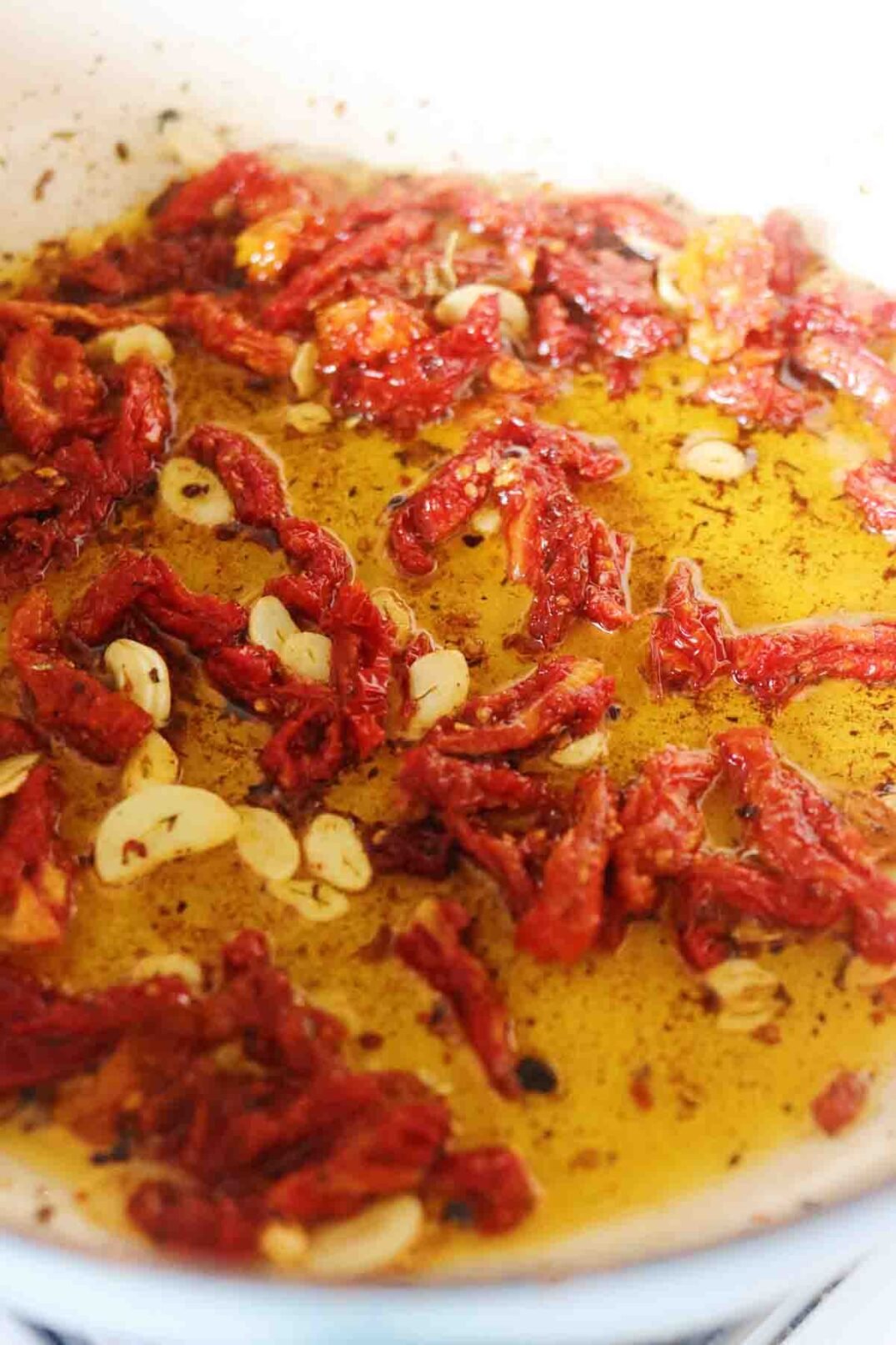 sun dried tomato, garlic and oil bubbling in a sauce pan.
