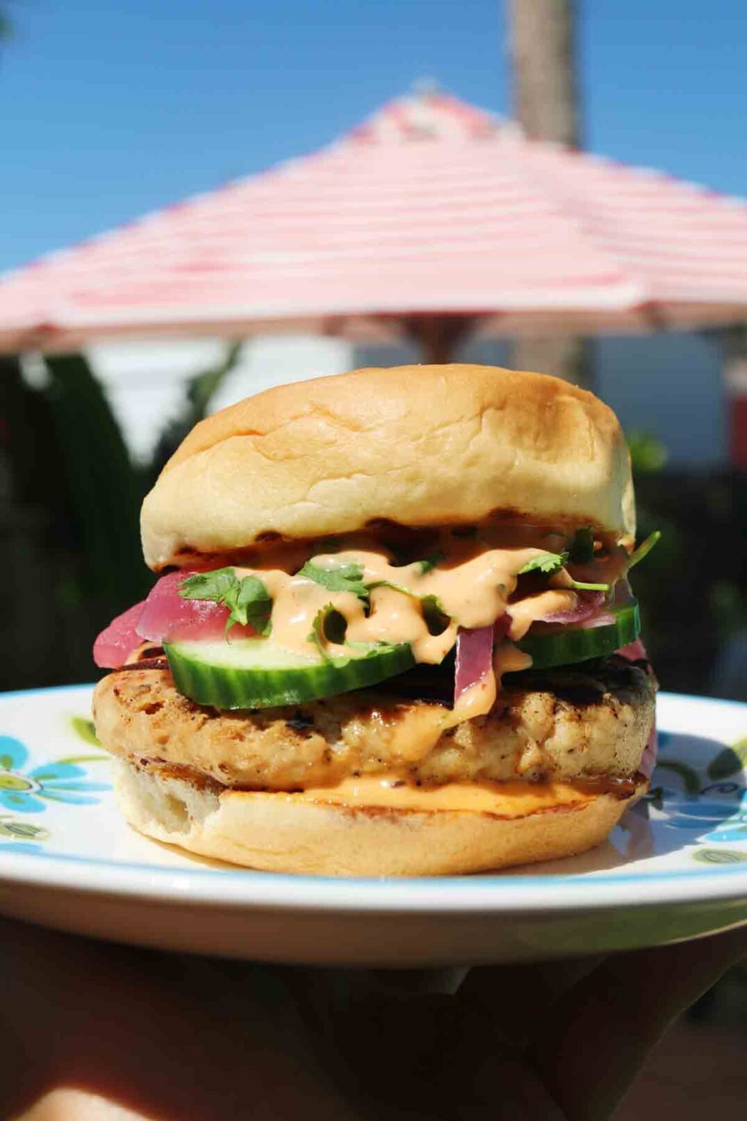 a teriyaki turkey burger in front of a red and white umbrella.