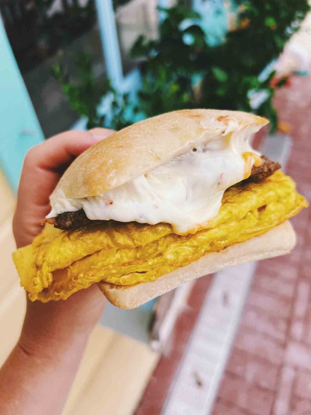 a hand holding the bubble room breakfast sandwich on ciabatta bread.