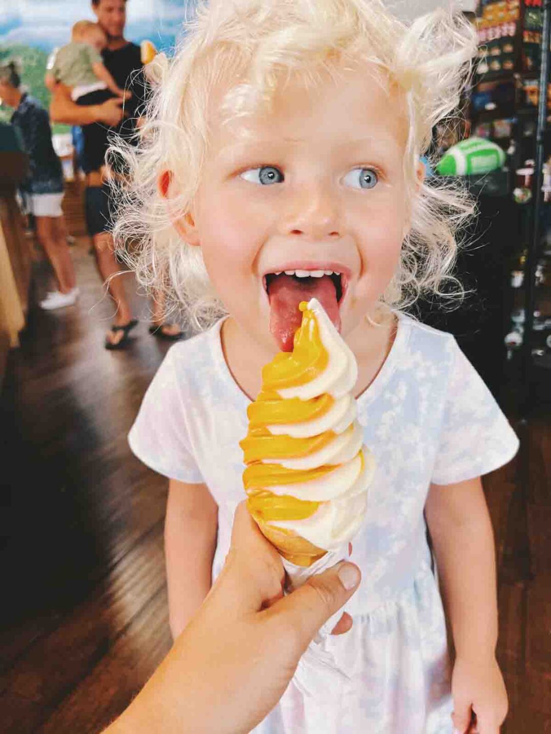 a little girl eating a orange vanilla swirl ice cream cone from sun harvest in fort myers florida