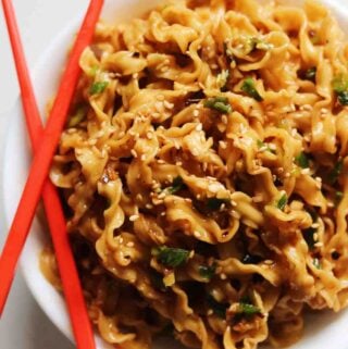 Trader Joe's Squiggly Knife Cut Noodles dressed in a brown sauce with red chopsticks.